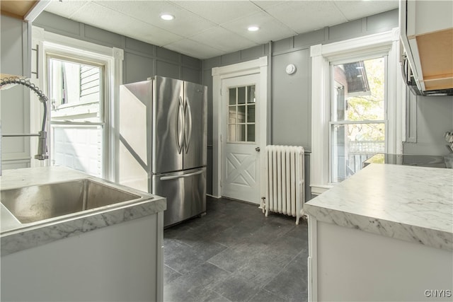 kitchen featuring stainless steel fridge, a healthy amount of sunlight, sink, and radiator