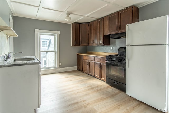 kitchen featuring black gas range, white refrigerator, light hardwood / wood-style floors, and sink