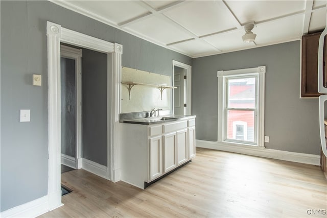 kitchen with white cabinets, light wood-type flooring, coffered ceiling, and sink