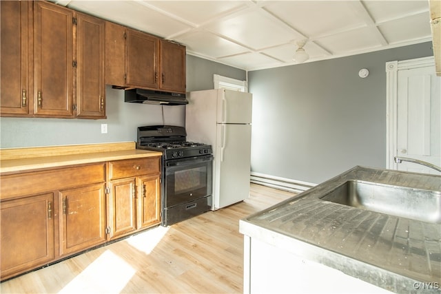 kitchen with gas stove, a baseboard heating unit, sink, light hardwood / wood-style flooring, and white fridge