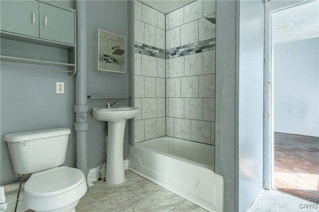 full bathroom featuring toilet, tiled shower / bath, and sink