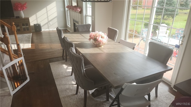 dining space with dark wood-type flooring and a tiled fireplace