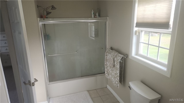 bathroom featuring tile patterned flooring, toilet, and shower / bath combination with glass door