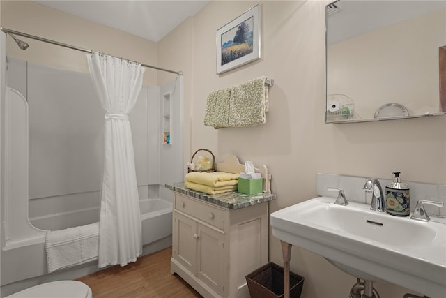 full bathroom featuring toilet, shower / bath combo with shower curtain, wood-type flooring, and sink