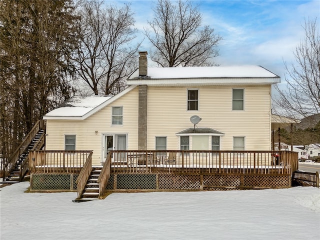 snow covered back of property with a wooden deck