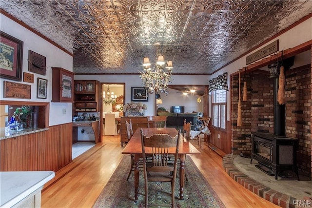 dining space featuring a chandelier, light wood-type flooring, a wood stove, and ornamental molding