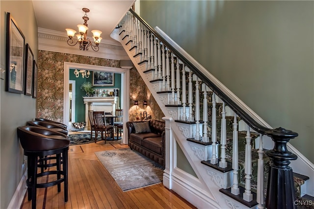 stairs featuring hardwood / wood-style flooring, ornamental molding, and a chandelier