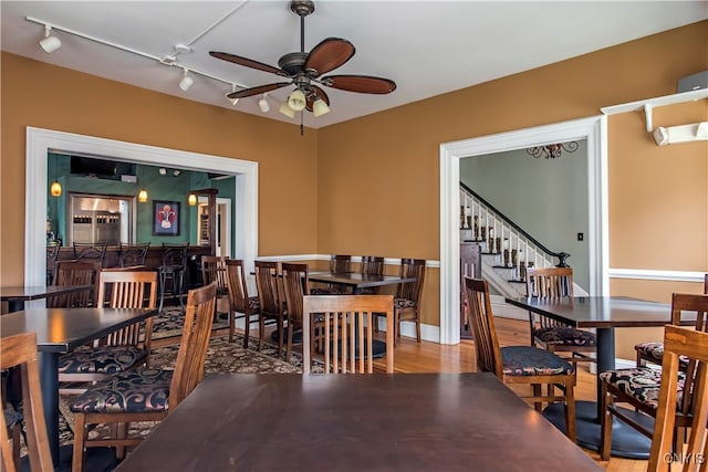 dining space with hardwood / wood-style flooring, ceiling fan, and track lighting