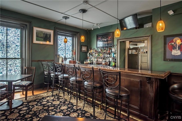 bar with built in refrigerator, pendant lighting, and hardwood / wood-style flooring