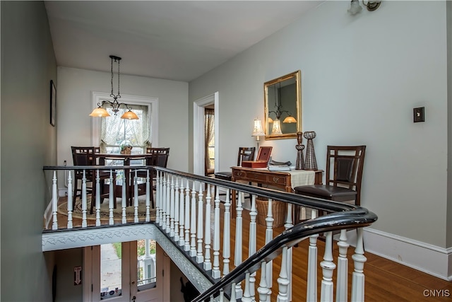 hall featuring plenty of natural light, hardwood / wood-style floors, and an inviting chandelier