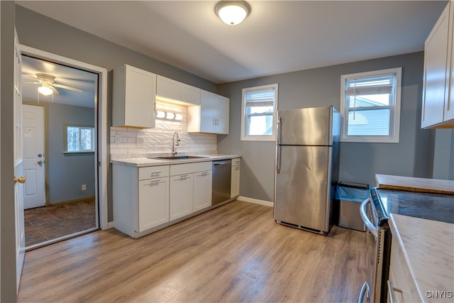 kitchen featuring appliances with stainless steel finishes, light hardwood / wood-style floors, white cabinetry, and sink