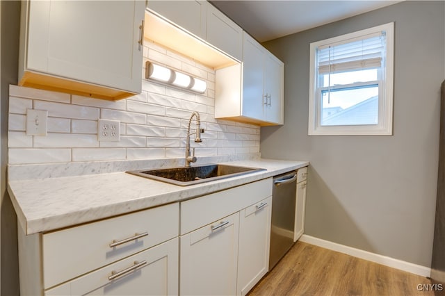 kitchen featuring white cabinetry, sink, tasteful backsplash, stainless steel dishwasher, and light hardwood / wood-style floors