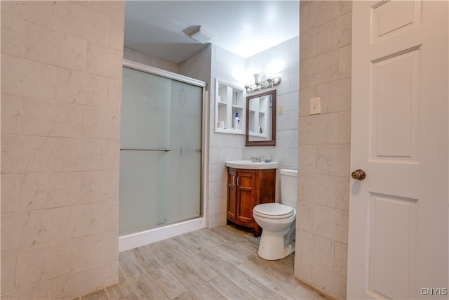 bathroom with vanity, hardwood / wood-style flooring, toilet, tile walls, and an enclosed shower