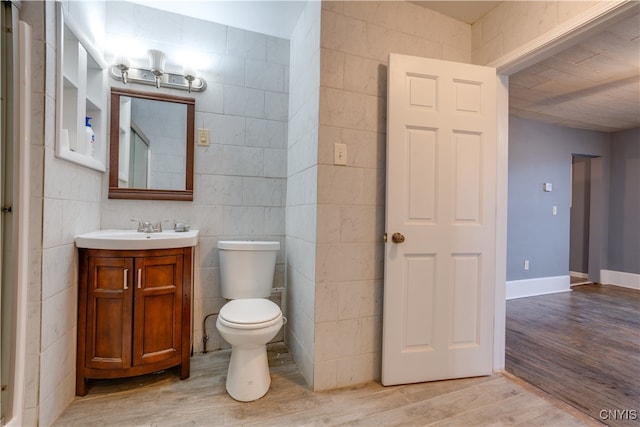 bathroom featuring vanity, wood-type flooring, tile walls, and toilet