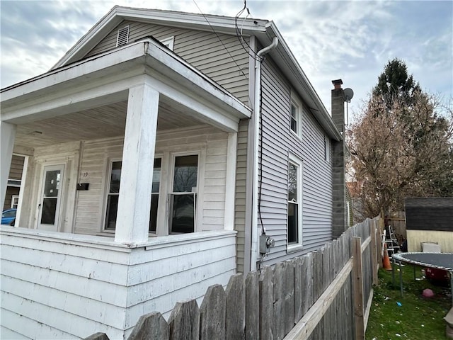 19 Jay St, Phelps, NY 14532 - view of side of home featuring a storage unit, a chimney, and a porch