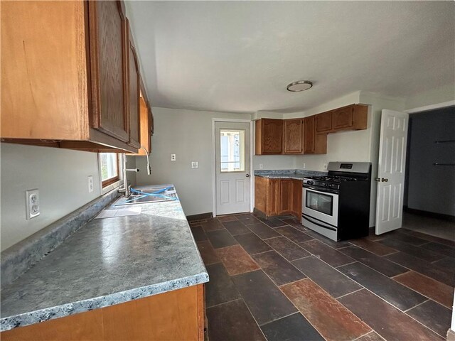 19 Jay St, Phelps, NY 14532 - kitchen with stainless steel gas range, brown cabinetry, and dark stone finish floors