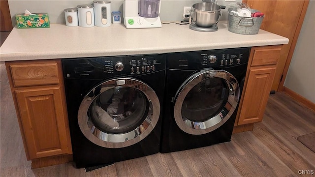 laundry area with hardwood / wood-style floors, cabinets, and independent washer and dryer