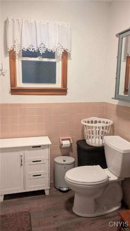 bathroom featuring vanity, hardwood / wood-style flooring, toilet, and tile walls