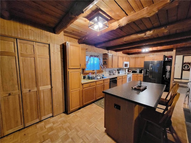 kitchen featuring beam ceiling, wooden walls, a center island, and black appliances