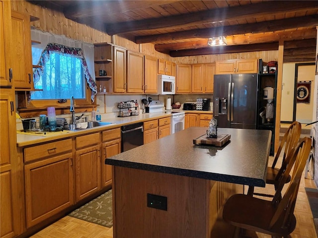 kitchen with beamed ceiling, a breakfast bar, a kitchen island, and white appliances