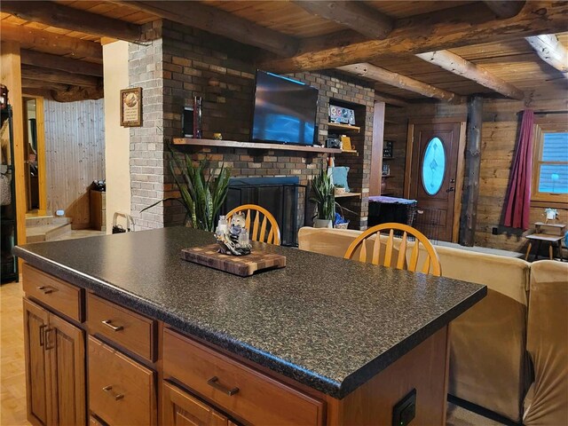 kitchen featuring beam ceiling, wood ceiling, wooden walls, and a brick fireplace