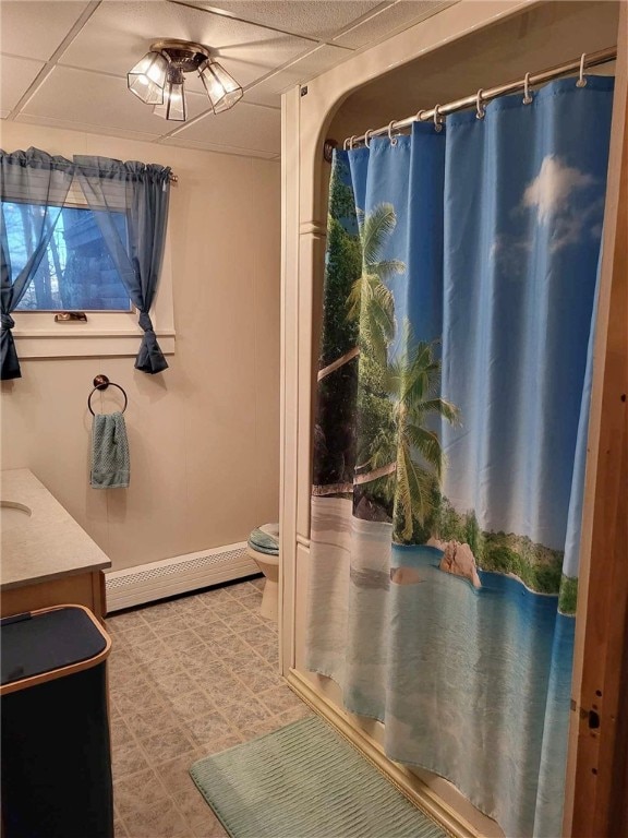 bathroom featuring a paneled ceiling, vanity, a baseboard radiator, toilet, and curtained shower