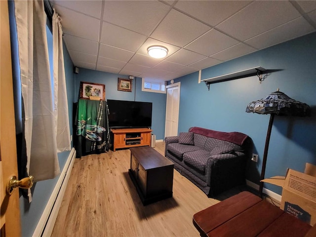 living room featuring a paneled ceiling, light hardwood / wood-style flooring, and a baseboard radiator