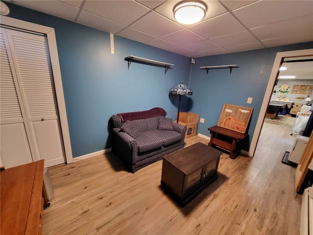 living room featuring a paneled ceiling and light hardwood / wood-style flooring