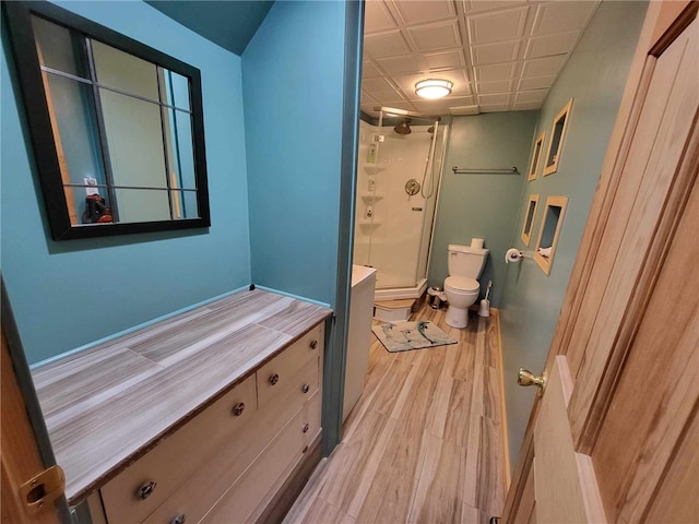 bathroom with wood-type flooring, vanity, toilet, and a shower with door