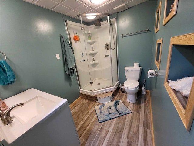 bathroom with hardwood / wood-style floors, vanity, toilet, and a shower with shower door