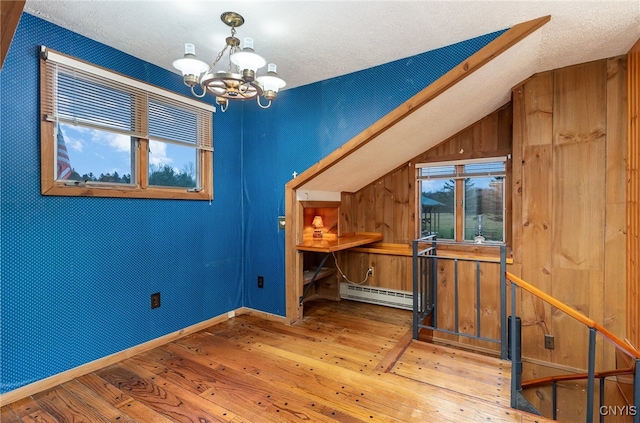 interior space featuring baseboard heating, wood-type flooring, a textured ceiling, and an inviting chandelier