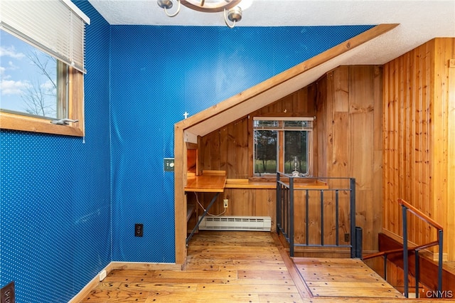 bonus room with hardwood / wood-style floors, wood walls, baseboard heating, and a textured ceiling