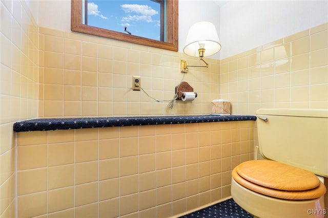 bathroom featuring toilet and tile walls