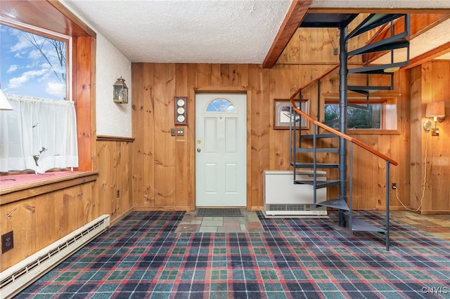 foyer with baseboard heating, wood walls, and a textured ceiling