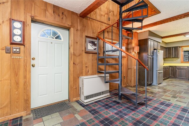 entryway featuring a textured ceiling, heating unit, and wooden walls