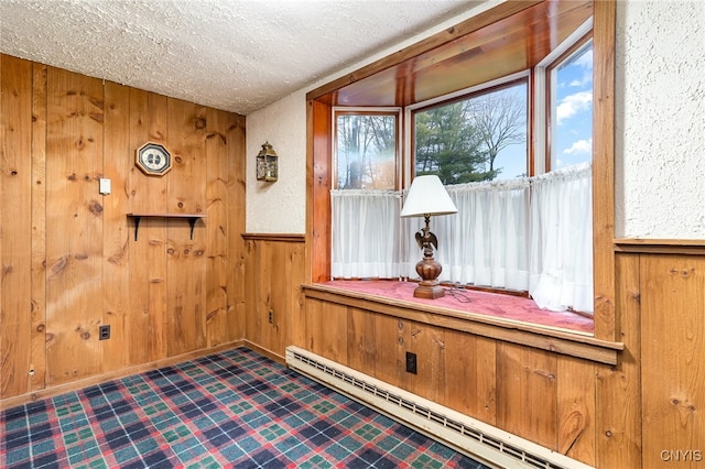 living area with a textured ceiling, wooden walls, and a baseboard radiator