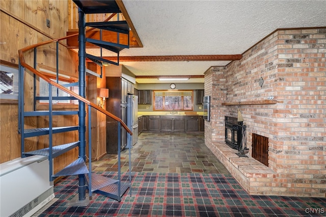 unfurnished living room featuring beamed ceiling, sink, and a textured ceiling