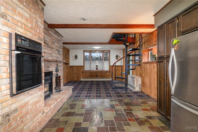 kitchen featuring stainless steel fridge, a textured ceiling, wooden walls, beamed ceiling, and oven