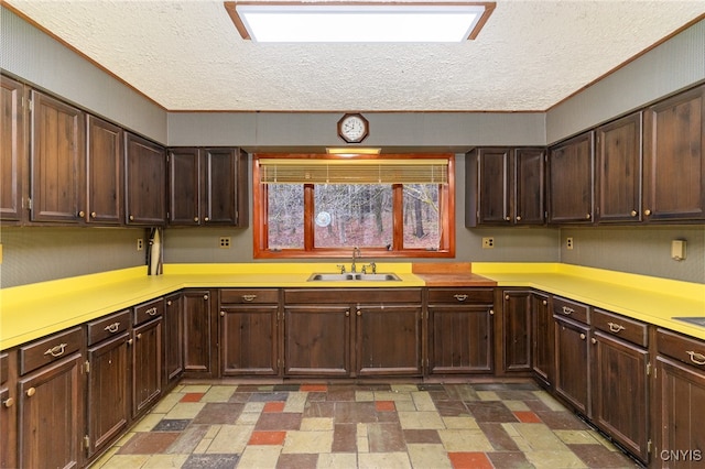 kitchen with dark brown cabinets, sink, and a textured ceiling