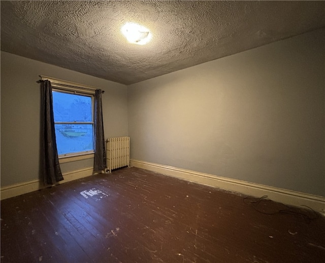 empty room featuring a textured ceiling, dark wood-type flooring, and radiator