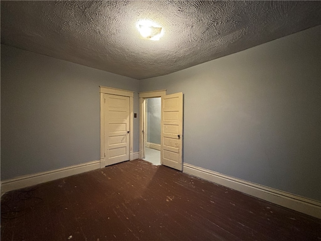 unfurnished bedroom featuring a textured ceiling and dark hardwood / wood-style floors