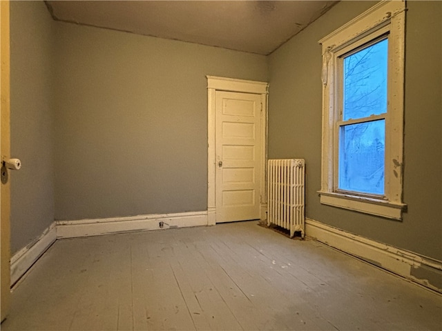 spare room featuring radiator heating unit and wood-type flooring