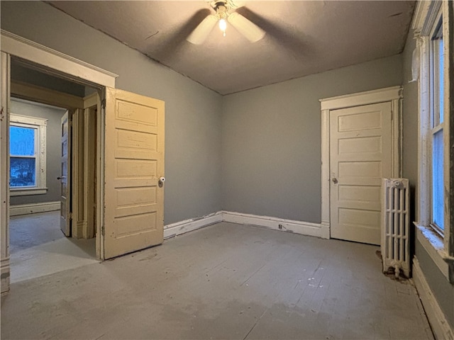 unfurnished room featuring ceiling fan, radiator heating unit, and plenty of natural light