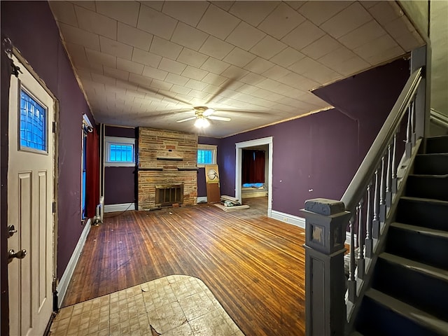 unfurnished living room with a fireplace, wood-type flooring, and ceiling fan