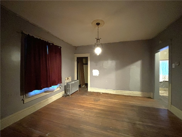 unfurnished dining area featuring radiator heating unit and hardwood / wood-style flooring