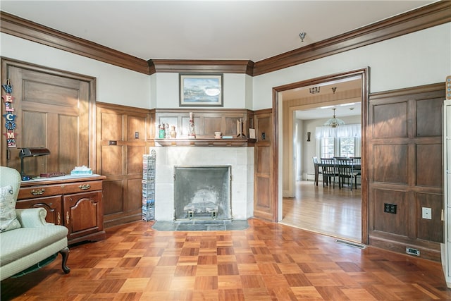 living room with light parquet floors, crown molding, and a tiled fireplace