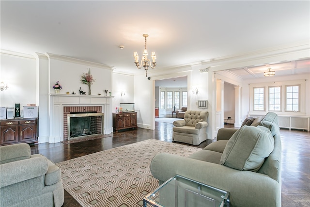 living room featuring a brick fireplace, a baseboard heating unit, dark wood-type flooring, crown molding, and a chandelier