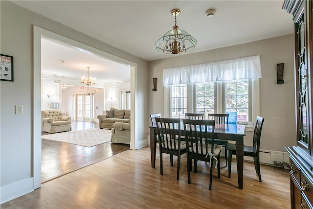 dining space with hardwood / wood-style floors, crown molding, a healthy amount of sunlight, and a notable chandelier