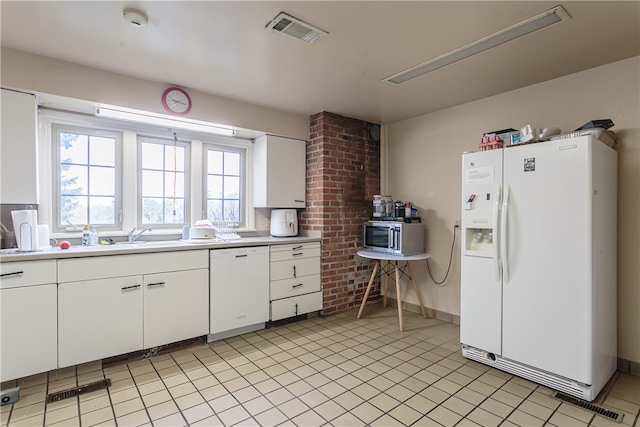 kitchen featuring light tile patterned floors, white appliances, white cabinetry, and sink