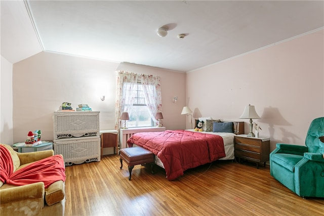 bedroom featuring hardwood / wood-style floors, lofted ceiling, and ornamental molding